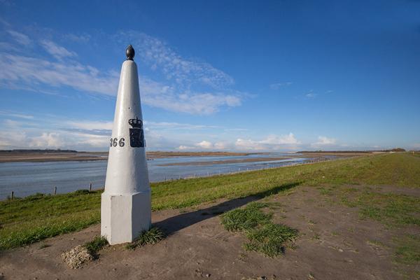 Grenspaal met op de achtergrond de zee